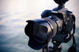 Professionelle Kamera mit Teleobjektiv am Stativ, bereit für Fotografie im Freien.